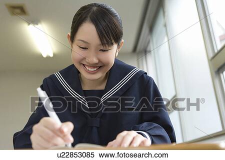 Stock Photography - Teenage girl studying at desk, smiling. Fotosearch