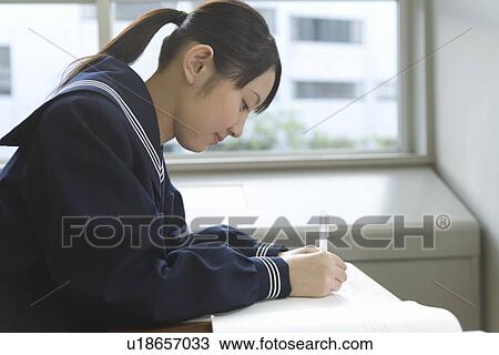 Stock Image - Teenage girl studying at desk. Fotosearch