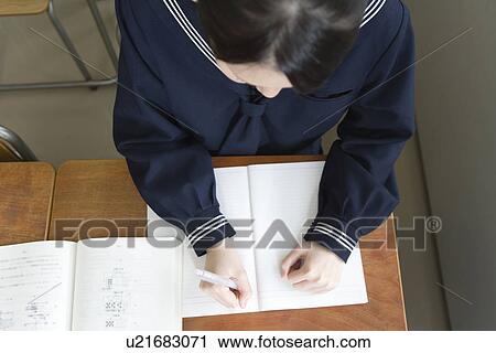 Stock Image - Teenage girl studying at desk. Fotosearch