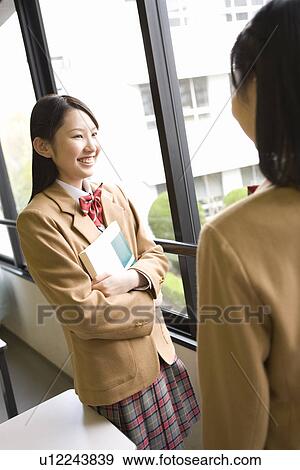 Stock Photo - Teenage girls standing beside the window and talking. Fotosearch