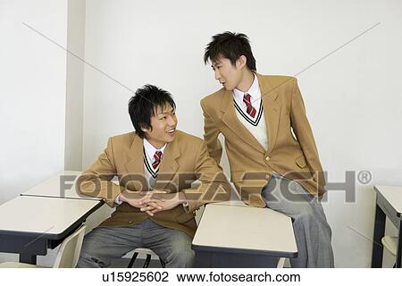 Two teenage boys sitting at desk and talking in classroom View Large Photo Image Stock Image - Two teenage boys sitting at desk and talking in classroom. Fotosearch