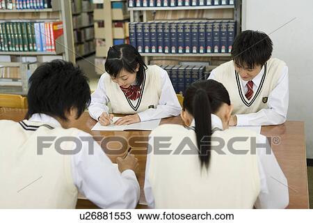 Stock Image - Four teenagers studying in library. Fotosearch