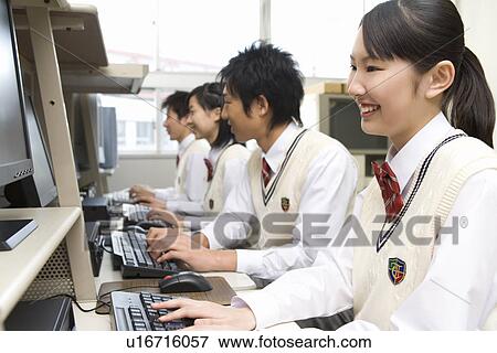 Stock Photo - Four teenagers using personal computers in library, smiling, side by side. Fotosearch