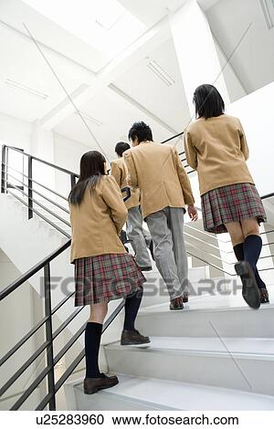 Stock Image - Four teenagers walking up the stairs in school. Fotosearch