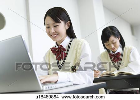 High school students sitting at desk in class, girl using laptop View Large Photo Image Picture - High school students sitting at desk in class, girl using laptop. Fotosearch