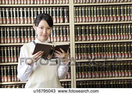 Portrait of a teenage girl holding a book in front of bookcase, smiling and looking at camera View Large Photo Image Stock Image - Portrait of a teenage girl holding a book in front of bookcase, smiling and looking at camera. Fotosearch