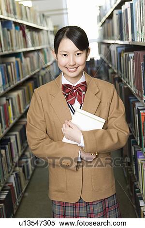 Portrait of a teenage girl holding a book in library, smiling and looking at camera View Large Photo Image Stock Photography - Portrait of a teenage girl holding a book in library, smiling and looking at camera. Fotosearch