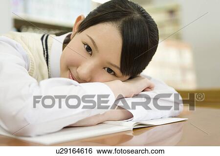 Portrait of a teenage girl resting at table in library, smiling and looking at camera View Large Photo Image Stock Photograph - Portrait of a teenage girl resting at table in library, smiling and looking at camera. Fotosearch