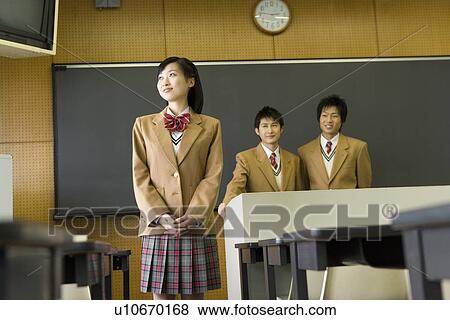 Stock Photo - Portrait of three high school students standing in classroom, smiling. Fotosearch