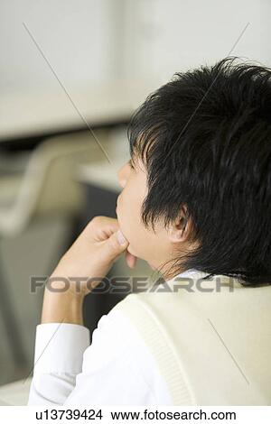 Picture - Teenage boy sitting at desk in classroom. Fotosearch
