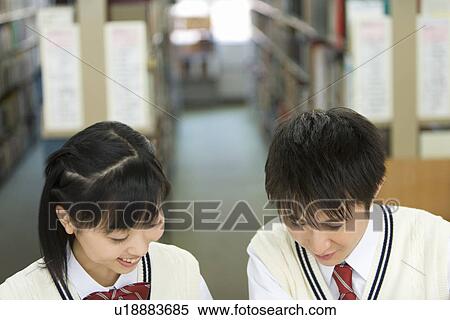 Teenage couple sitting at table in library, smiling View Large Photo Image Stock Photography - Teenage couple sitting at table in library, smiling. Fotosearch
