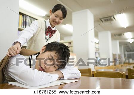 Teenage girl putting jacket on boy sleeping at table in library View Large Photo Image Stock Photography - Teenage girl putting jacket on boy sleeping at table in library. Fotosearch