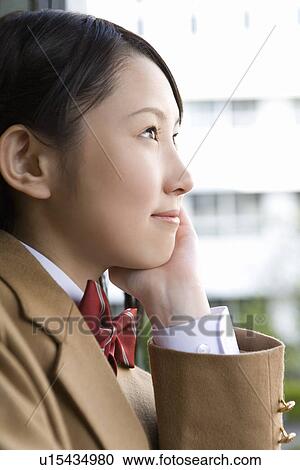 Stock Image - Teenage girl resting chin in hand, smiling. Fotosearch