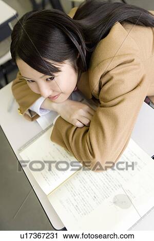 Teenage girl sitting and leaning on desk in classroom, smiling View Large Photo Image Stock Image - Teenage girl sitting and leaning on desk in classroom, smiling. Fotosearch