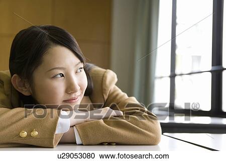 Teenage girl sitting and leaning on desk in classroom, smiling and looking away View Large Photo Image Stock Image - Teenage girl sitting and leaning on desk in classroom, smiling and looking away. Fotosearch
