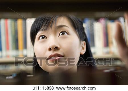 Teenage girl standing between bookcases View Large Photo Image Stock Photo - Teenage girl standing between bookcases. Fotosearch