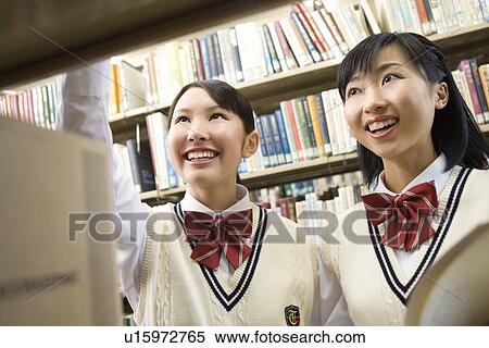 Teenage girls smiling and standing between bookcases View Large Photo Image Stock Photography - Teenage girls smiling and standing between bookcases. Fotosearch