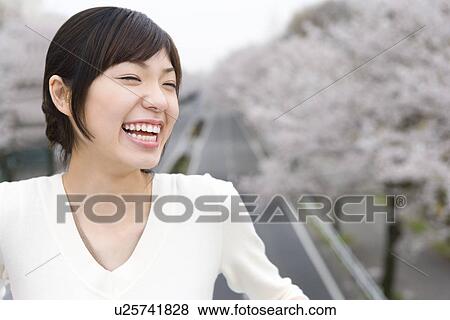 Portrait of a woman smiling, road lined with cherry trees in the background, front view, Japan View Large Photo Image Stock Photo - Portrait of a woman smiling, road lined with cherry trees in the background, front view, Japan. Fotosearch