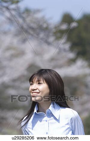 Stock Photograph - Young Woman and Cherry blossom, Differential Focus. Fotosearch