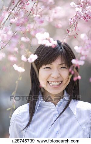 Stock Photo - Young Woman and Weeping Cherry Trees, Differential Focus, Front View. Fotosearch
