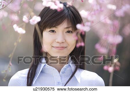 Stock Photography - Young Woman and Weeping Cherry Trees, Differential Focus, Front View. Fotosearch