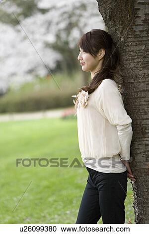 Stock Image - Young Woman Leaning on Wood, Differential Focus, . Fotosearch