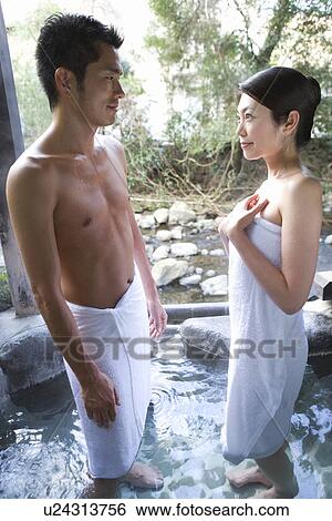 Stock Photograph - Japanese couple in towel looking at each other in a hot tub, smiling, side view, Japan. Fotosearch