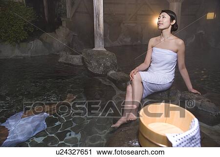 Stock Image - Japanese Woman in a hot tub, woman soaking her legs, front view, high angle view, Japan. Fotosearch