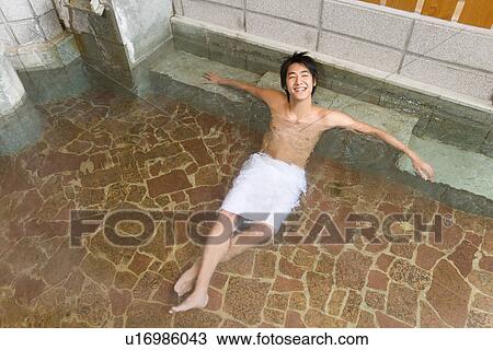 Stock Image - Man relaxing in hot tub, high angle view, Japan. Fotosearch