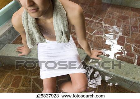 Stock Image - Man soaking legs in hot tub, high angle view, Japan. Fotosearch
