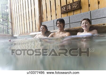 Stock Photography - Portrait of man and women relaxing in hot tub, front view, Japan. Fotosearch