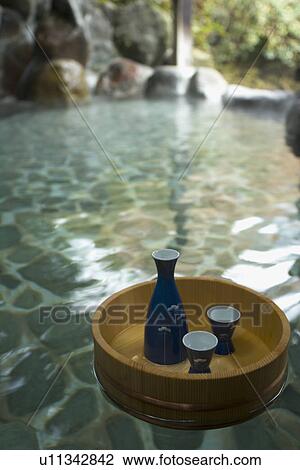 Sake bottle and cups in a wooden tub floating on a Japanese common tub, hot spring, high angle view, Japan View Large Photo Image Stock Image - Sake bottle and cups in a wooden tub floating on a Japanese common tub, hot spring, high angle view, Japan. Fotosearch