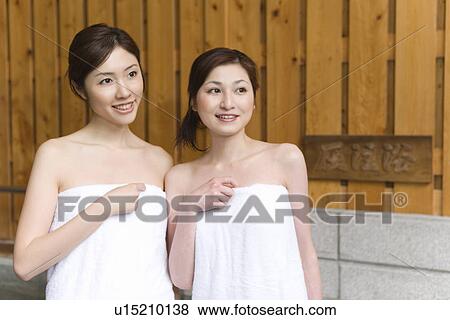 Stock Photo - Two women in towel standing side by side, smiling, front view, Japan. Fotosearch