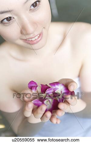 Stock Photography - Woman in hot tub holding flower heads, high angle view, close up, Japan. Fotosearch