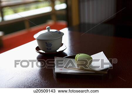 Stock Image - High Angle View of a Tea Cup and Sweet, Differential Focus. Fotosearch