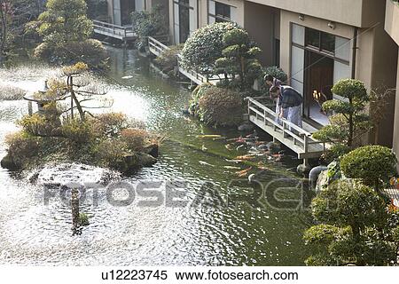 Stock Photography - Mature Adult Couple Looking at Carp from the Wooden Balcony, Side View, High Angle View, Full Length. Fotosearch