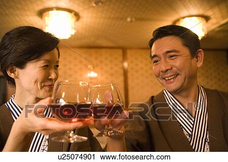Stock Image - Mature Adult Couple Toasting With Brandy, Front View, Head and Shoulder. Fotosearch