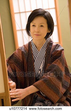 Picture - Mature Adult Woman Sitting and Opening the Sliding Door, Front View, Waist Up. Fotosearch