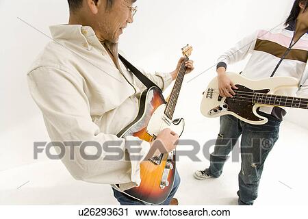 Stock Image - A Father and His Son Playing Guitars Together, Front View, Side View, Studio Shot. Fotosearch
