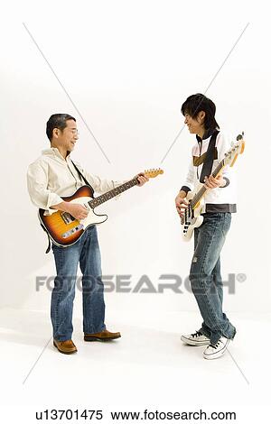 Stock Photography - A Father and His Son Playing Guitars Together, Side View. Fotosearch