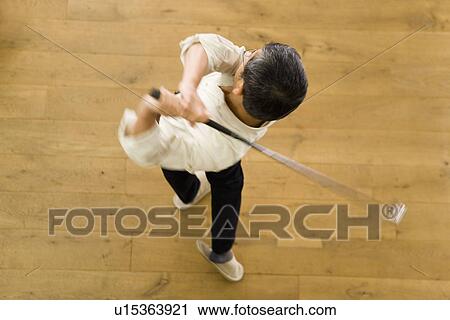 Stock Image - A Mature Adult Man Swinging a Golf Club, High Angle View, Blurred Motion. Fotosearch