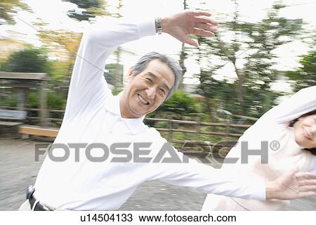 Stock Image - A Senior Adult Couple Enjoying an Exercise Together, Front View, Panning. Fotosearch