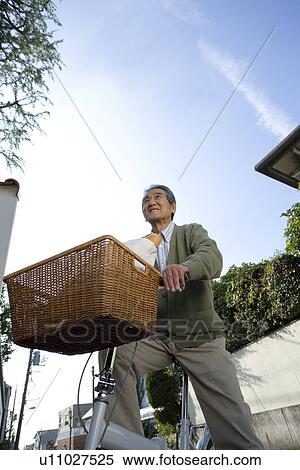 Stock Photography - A Senior Adult Man on a Bicycle Under the Blue Sky, Low Angle View. Fotosearch
