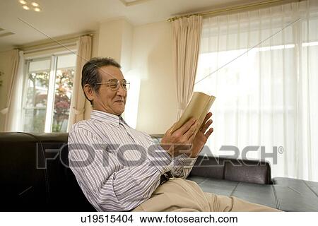 A Senior Adult Man Reading a Book in a Living Room, Side View, Low Angle View View Large Photo Image Picture - A Senior Adult Man Reading a Book in a Living Room, Side View, Low Angle View. Fotosearch