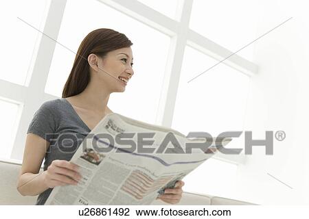 A woman holding newspaper, smiling and looking away, side view, low angle view View Large Photo Image Stock Image - A woman holding newspaper, smiling and looking away, side view, low angle view. Fotosearch