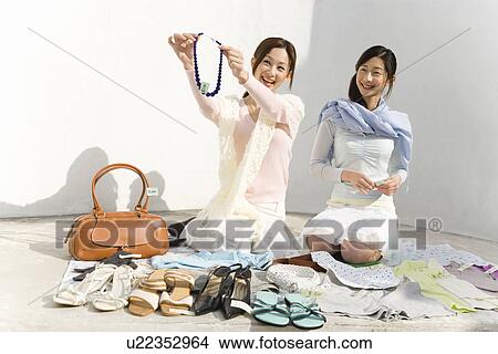 Two women smiling and selling their stuff at a flea market, one holding a necklace, front view, white background View Large Photo Image Picture - Two women smiling and selling their stuff at a flea market, one holding a necklace, front view, white background. Fotosearch