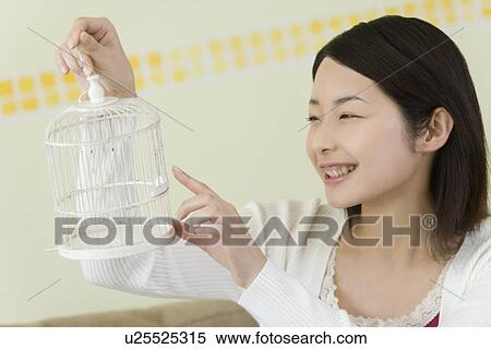 Stock Photography - Woman holding a birdcage, side view. Fotosearch
