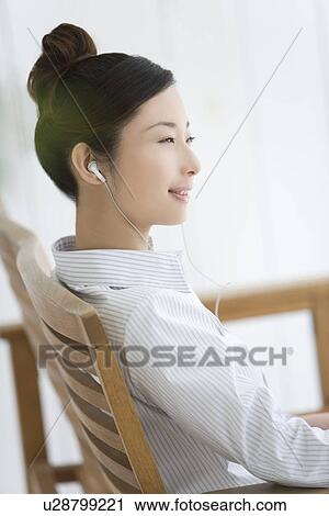 Woman sitting and listening to music, smiling, side view View Large Photo Image Stock Image - Woman sitting and listening to music, smiling, side view. Fotosearch