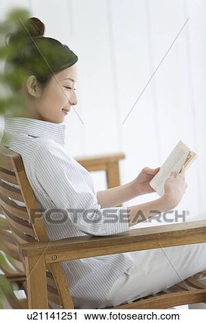 Woman sitting and reading a book, smiling, side view View Large Photo Image Stock Image - Woman sitting and reading a book, smiling, side view. Fotosearch