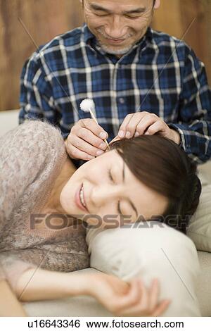 Stock Photograph - A Mature Adult Man Cleaning His Wife's Ear, Front View, Differential Focus, Close Up. Fotosearch